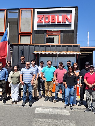 Mitarbeitende stehen vor einem Gebäude mit ZÜBLIN-Logo.