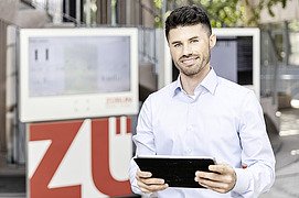 Foto von einem Mann, der ein Tablet hält und lächelt  