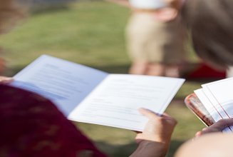 Nahaufnahme von Personen, die sich ein Programmheft anschauen.