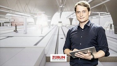 Foto von einem Mann, der vor einem BIM-Modell steht und lächelt 