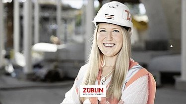 Foto von einer lächelnde Frau mit Bauhelm auf der Baustelle 