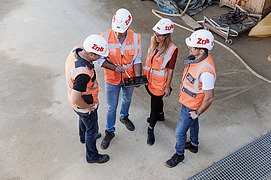 Foto von vier Mitarbeitende auf der Baustelle, die im Gespräch sind