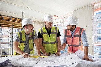Polierprogramme bei ZÜBLIN Foto von drei Polieren, die vor einem Bauplan stehen und sich besprechen.