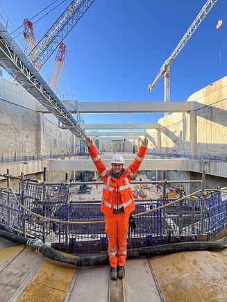 Junge Frau in Arbeitsschutzkleidung auf einer Baustelle.