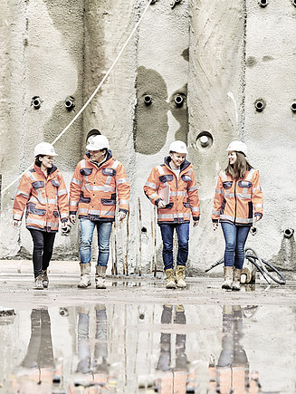 Foto von vier Mitarbeitende mit Arbeitsschutzkleidung auf der Baustelle