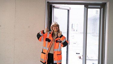 Junge ZÜBLIN Mitarbeiterin mit PSA auf einer Baustelle.