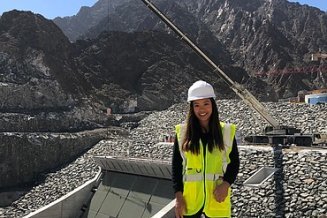 Junge Frau mit Warnweste steht vor einem Bauwerk.