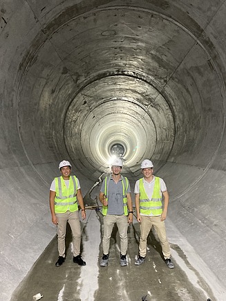 Drei Personen mit Bauhelm stehen in einem Tunnel