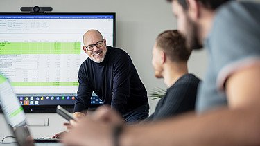 Photo of a member of staff standing in front of a digital building plan.