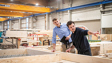 Two staff members are inspecting wooden components