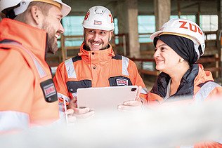 Zwei Mitarbeiter in Arbeitsschutzkleidung auf einer Baustelle in einer Besprechungssituation