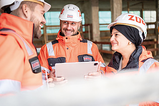 Two employees wearing high-visibility clothing on a building site, in the middle of a meeting