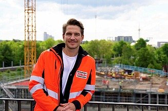 A young man in high-visibility workwear standing in front of a white wall