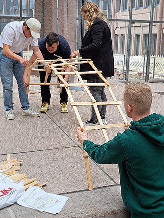 Vier junge Personen bauen eine Leonardobrücke