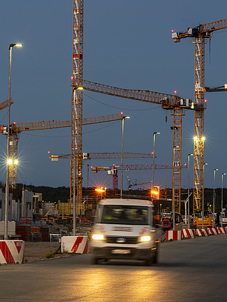 Bild von einer Baustelle, im Hintergrund sind mehrere Kräne zu sehen