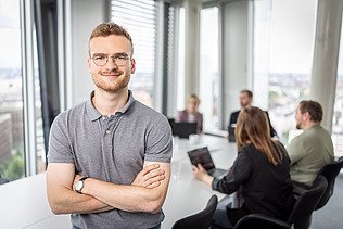 A meeting scene, with an employee in the foreground with their arms crossed