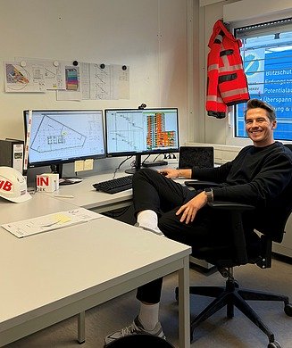 Mitarbeiter sitzt an seinem Schreibtisch im Baucontainer