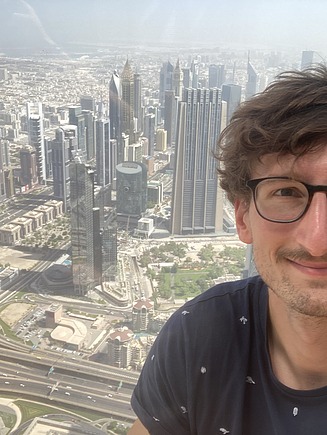 Männliche Person auf dem Burj Khalifa mit Skyline im Hintergrund