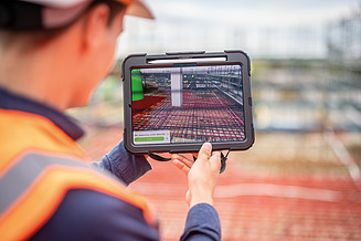 Ein Kollege hält ein iPad mit Bauzeichnungen in der Hand.