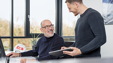 A photo of two ZÜBLIN staff members in the office, chatting.