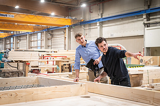 Two staff members are inspecting wooden components