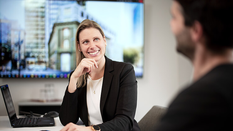 Foto von einer Projektleiterin, die in einem Meetingraum sitzt.