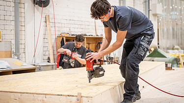 Two apprentices working on wooden components