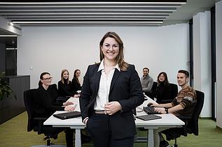 ZÜBLIN Mitarbeiterin, die vor Konferenztisch im Büro steht und in die Kamera lächelt