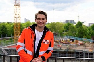 Junger Mann in Arbeitsschutzkleidung vor einer weißen Wand