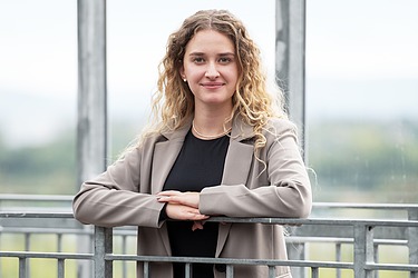 Junge Frau mit den Armen auf einem Geländer abgestützt