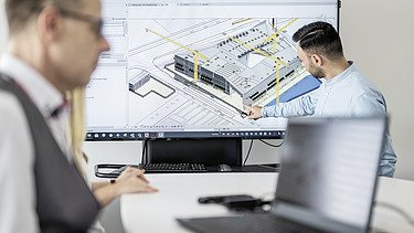 Direkteinstieg_bei_ZÜBLIN_Informationstechnologie Foto von einem Mitarbeitenden vor einem digitalen Bauplan.
