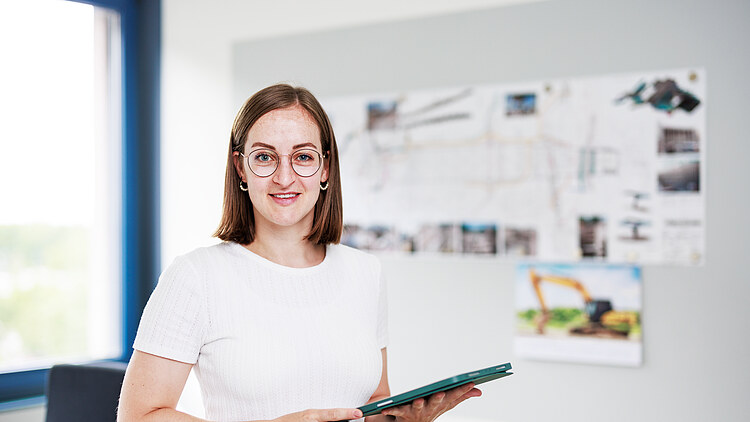 A young woman holding a tablet in an office