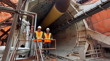 Two staff members in high-visibility clothing in front of a tunnel