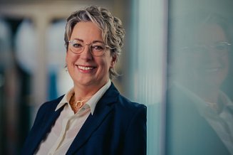 Vorständin Sabine Hahn lächelnd vor einem Bücherregal
