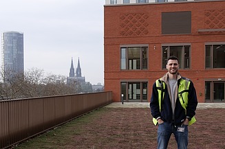 Site manager Philipp is standing in front of the ‘Rossio’ building; Cologne Cathedral can be seen in the background 