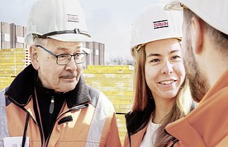 Foto von zwei Männern und einer Frau im Gespräch auf der Baustelle
