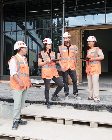 Menschen auf der Baustelle stehen zusammen.