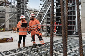 Abenteuer_Großbaustelle Zwei Mitarbeitende in Arbeitsschutzkleidung auf einer Großbaustelle.