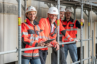 ZÜBLIN Mitarbeitende stehen in persönlicher Schutzausrüstung auf einem Baugerüst.