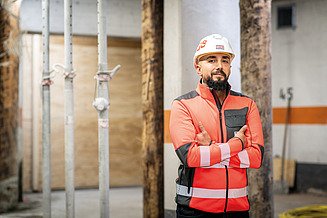 Mitarbeiter in Arbeitsschutzkleidung auf der Baustelle mit verschränkten Armen
