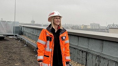 Junge ZÜBLIN Mitarbeiterin mit PSA auf einer Baustelle.
