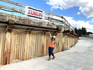 Mitarbeiterin in Arbeitsschutzkleidung, zeigt auf eine ZÜBLIN-Baustelle