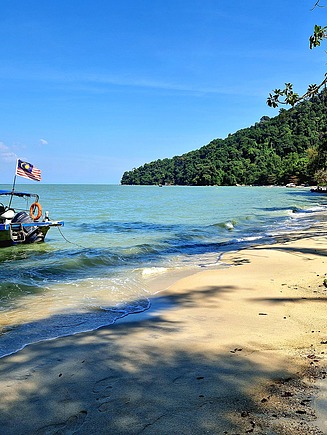 Strand in Malaysia, auf dem Wasser ist ein Boot zu sehen.