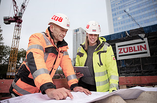 Photo of ZÜBLIN colleagues discussing something whilst looking at a construction plan