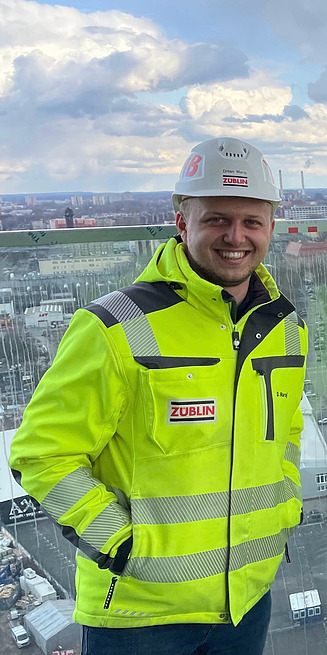 Junger Mann in Arbeitsschutzkleidung auf einer Baustelle in Berlin.