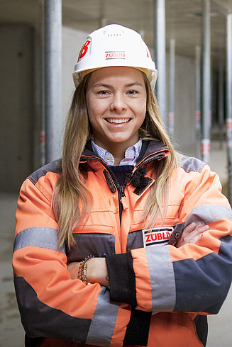 A woman in high-visibility clothing smiles at the camera