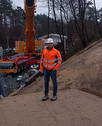 Mitarbeiter in Arbeitsschutzkleidung auf einer Baustelle vor einer großen Maschine