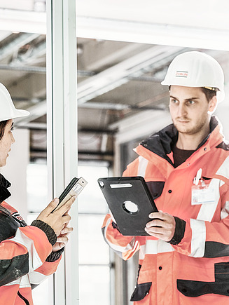 Photo of people in protective clothing holding tablets and looking at them