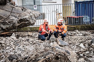Zwei Mitarbeiter in Arbeitsschutzkleidung auf einer Baustelle