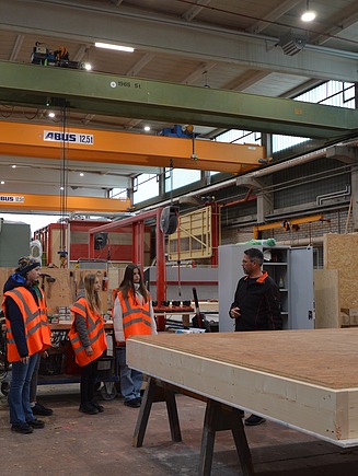 Kinder in Arbeitsschutzkleidung stehen in der Produktionshalle von ZÜBLIN Timber.